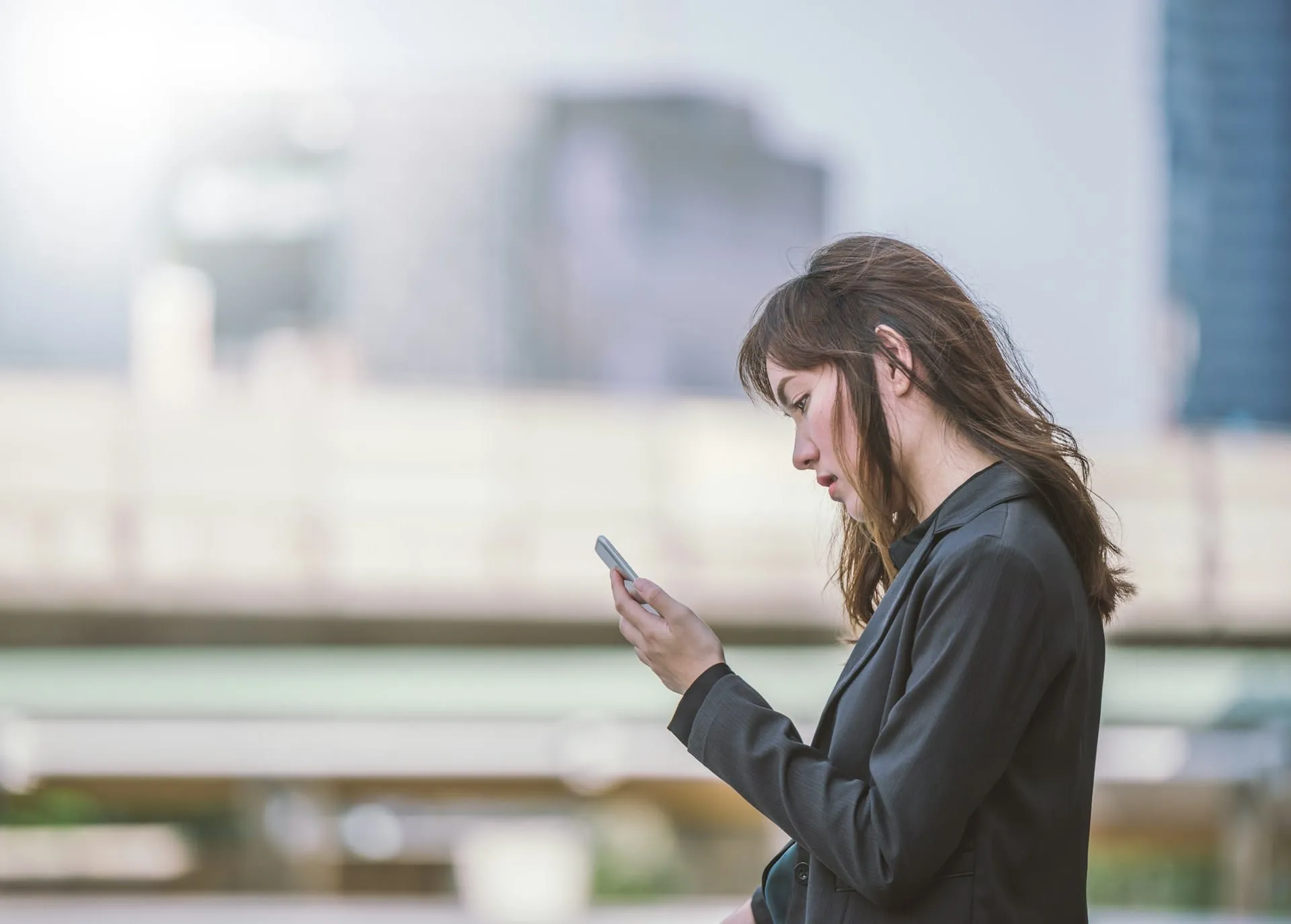 Woman outdoors reading a message on her phone, what to text someone whose pet died